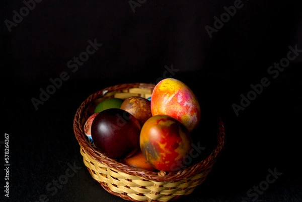 Obraz Colored easter eggs in a wooden basket on a black background