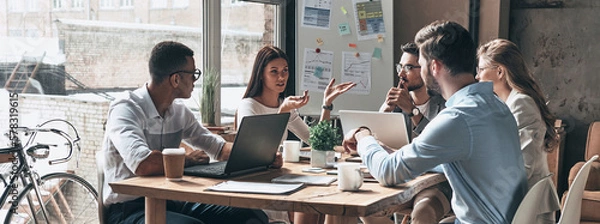 Obraz Group of young people discussing business together while having meeting in the office