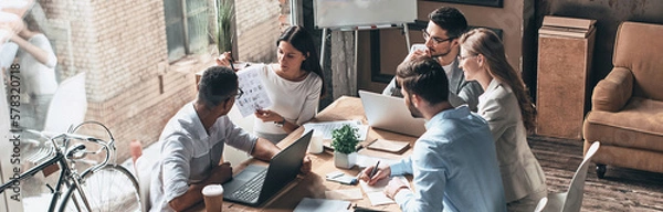 Obraz Group of young business people discussing strategy while having meeting in the office