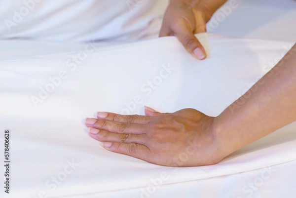 Obraz Female Hand set up white bed sheet in bedroom or maid hands making bed in a hotel room