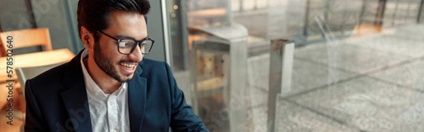 Obraz Indian businessman is making notes in notepad during working day in cafe. Blurred background