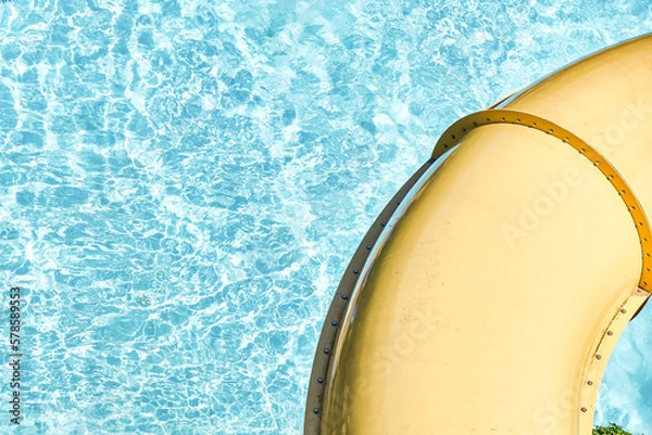 Obraz Water park slide pipe against blue clear water close up. Fun attractions for kids and adults in water park at summer resort