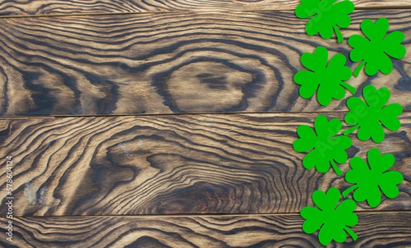 Fototapeta Frame of four-leaf clover and light lights. Wooden background with clover leaves. St. Patrick's Day. Textured wood, blank for holiday greetings. Flat layout. copy space.