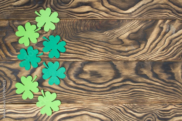 Fototapeta Frame of four-leaf clover and light lights. Wooden background with clover leaves. St. Patrick's Day. Textured wood, blank for holiday greetings. Flat layout. copy space.