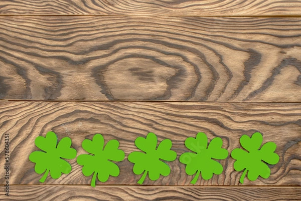 Fototapeta Frame of four-leaf clover and light lights. Wooden background with clover leaves. St. Patrick's Day. Textured wood, blank for holiday greetings. Flat layout. copy space.