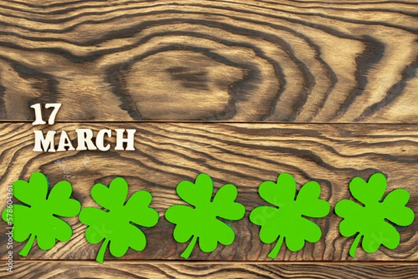 Fototapeta The inscription March 17 and a clover leaf on a dark wooden background. The concept of celebrating St. Patrick. Blank for congratulations on St. Patrick's Day. copy space. Flat layout.
