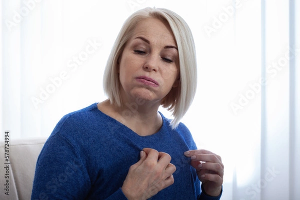 Obraz Mature woman experiencing hot flush from menopause. A woman in an uncomfortable position due to the discomfort of menopausal hot flushes