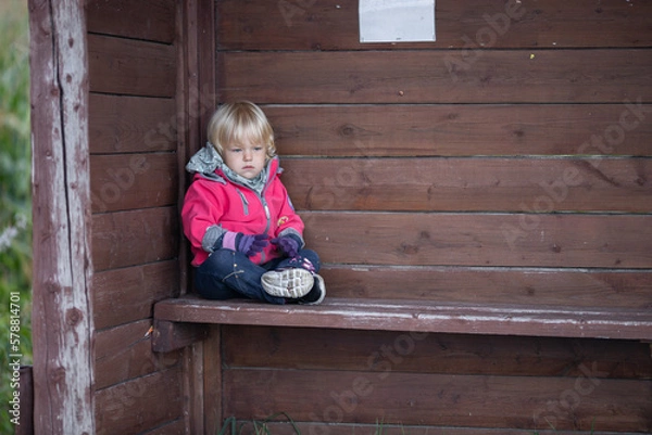 Obraz A little girl at a bus stop in a small idyllic village