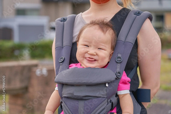 Obraz 抱っこ紐で抱っこされる笑顔の乳幼児