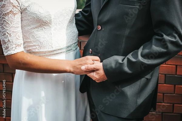 Fototapeta Close-up photo of the hands of the bride and groom, decorated with wedding rings. The beauty of their intertwined fingers. Rings on the hand of the bride and groom