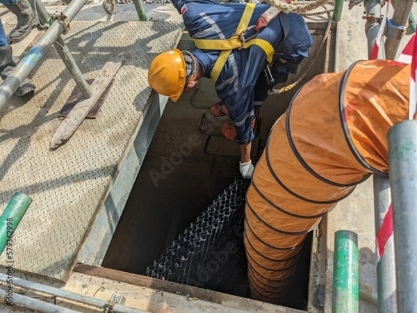 Obraz Worker install settler for oil on oil sparator pit with confine space. The photo is suitable to use for safety poster and safety content media.