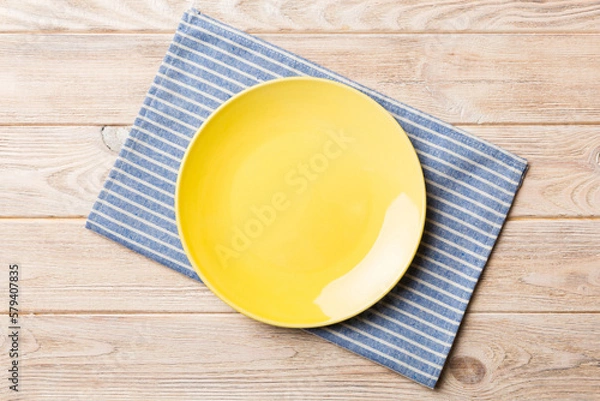Obraz Top view on colored background empty round yellow plate on tablecloth for food. Empty dish on napkin with space for your design