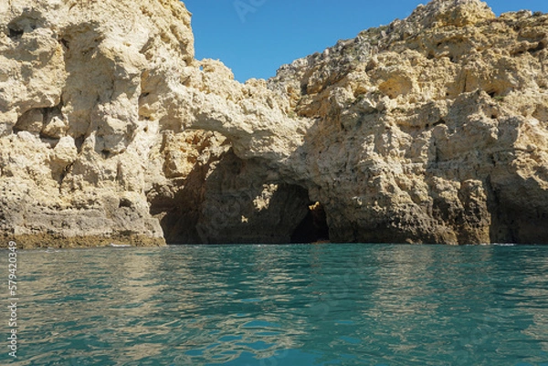 Obraz Stone Cliff caves in Portugal on a sunny day from the boat with teal water