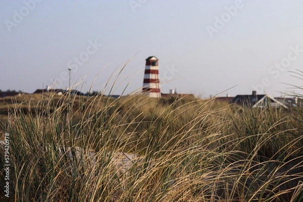 Obraz Lighthouse on the beach with tall grass in the wind