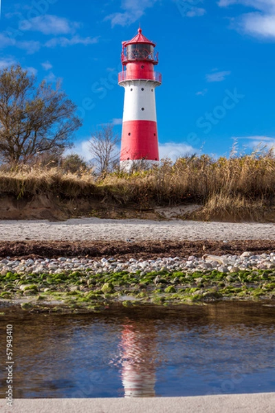 Fototapeta rot weisser leuchtturm vor blauem himmer wolken ostsee