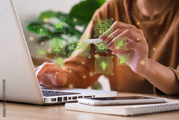 Obraz Businesswoman use a computer to analyze ESG, surrounded by ESG icons close to the computer screen in business investment strategy concept. environment social governance investment business concept.