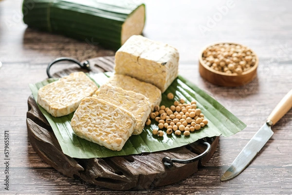 Fototapeta raw tempe or tempeh is a traditional  Indonesian food made from fermented soybeans.. Tempeh wrapped in banana leaf.