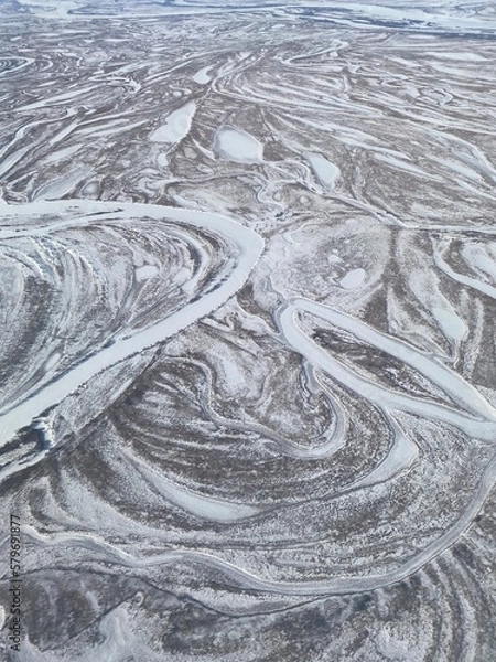 Fototapeta Abstract winter panorama with snow-covered territory - forests, fields and winding rivers.