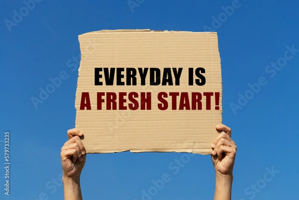 Obraz Everyday is a fresh start text on box paper held by 2 hands with isolated blue sky background. This message board can be used as business concept about new begining.