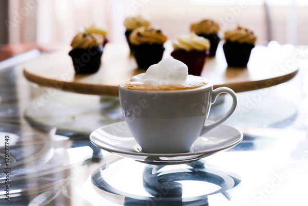 Fototapeta White cup of latte with mini chocolate cupcakes with peanut butter cream icing