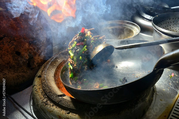Fototapeta A chef in Xinjiang is frying a delicacy quickly, the flames are flying and the aroma is overflowing
