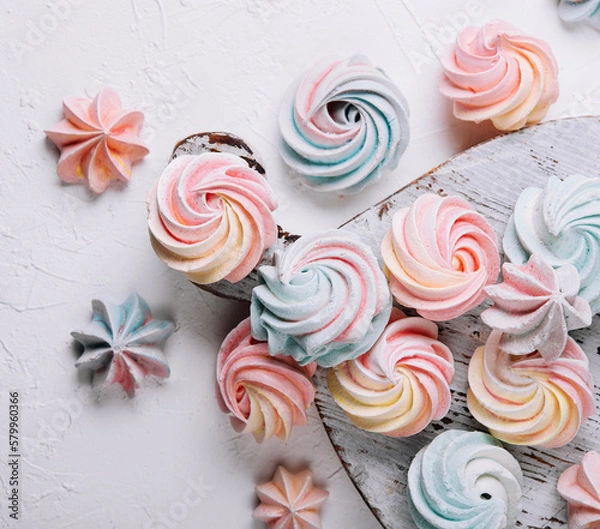 Fototapeta Multicolored meringue on wooden tray top view