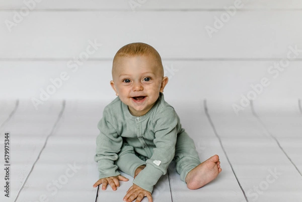 Obraz Lachender Junge sitzt am Boden 