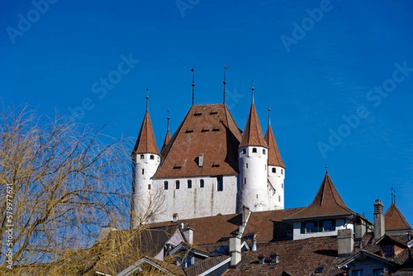 Fototapeta Old town of City of Thun with white castle on a hill in the background on a sunny winter day. Photo taken February 21st, 2023, Thun, Switzerland.