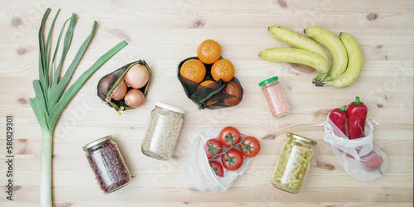 Fototapeta Vegetables and fruits in reusable bags and cereals, beans in glass jars on a wooden table. The concept of zero waste and eco-friendly lifestyle. No plastic. Top view, flat lay, web banner