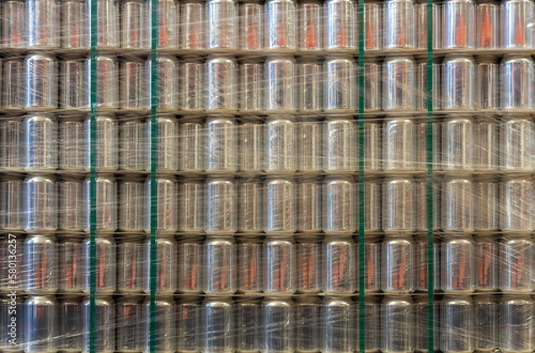 Fototapeta Background with a pallet of empty aluminum cans wrapped in film in a warehouse