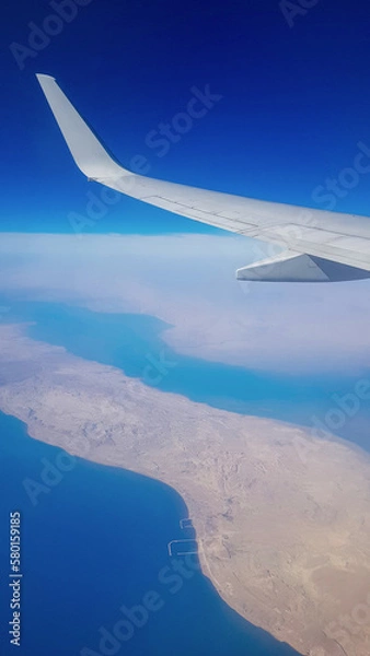 Fototapeta View from the window of plane on blue sky and earth with landscape of desert, sea and canals in Emirates. High quality photo
