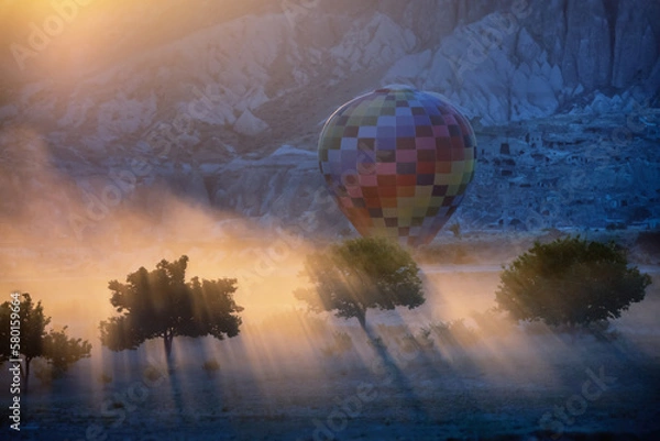 Fototapeta Balloon flight in Cappadocia mountains, Turkey. Contrasting silhouette of a tree in the rays of light
