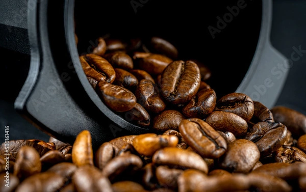 Obraz Dosing cup with black matte texture. Top view on black background with coffee beans. Barista tool for dosing coffee beans and using it to when grinding beans. Focus on the beans in the center