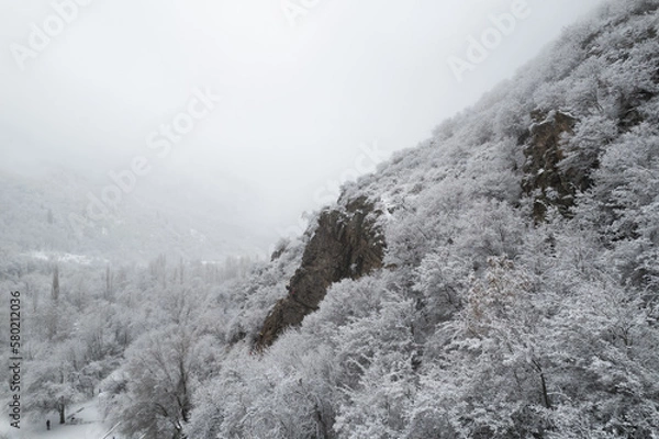 Fototapeta Aerial shot of snow covered cliffs conquered by climbers