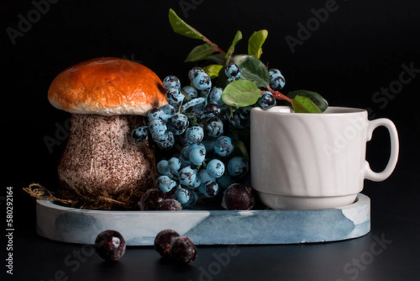 Fototapeta blueberries in a plate on a black background. Summer still life with porcini mushroom and berries