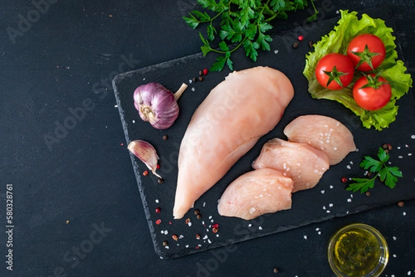 Fototapeta Fresh raw chicken fillet on cutting board with spices on black background
