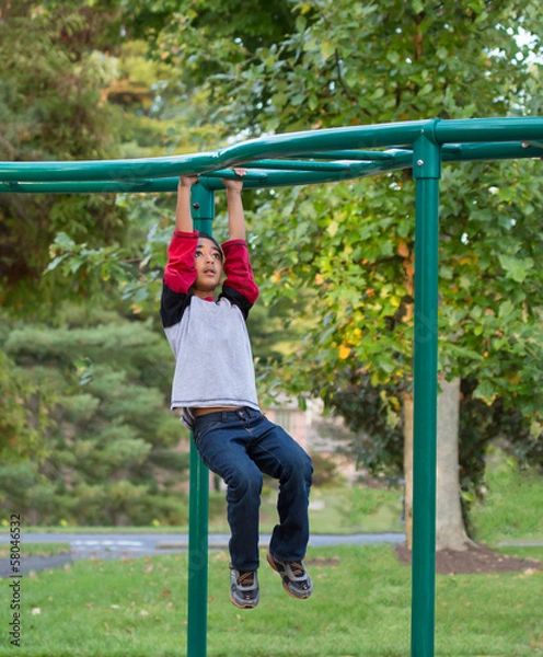 Fototapeta Child Hanging on Monkey Bars in Playground