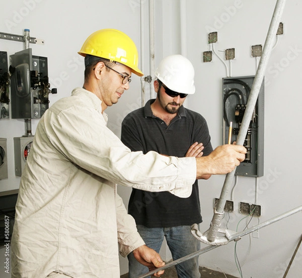 Fototapeta Electrician and foreman bending pipe for a job. 