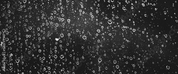 Fototapeta Atmospheric minimal grayscale backdrop with rain droplets on glass. Wet window with rainy drops and dirt spots closeup. Blurry minimalist monochrome background of dirty window glass with raindrops.