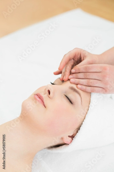 Fototapeta Hands massaging a beautiful woman's forehead