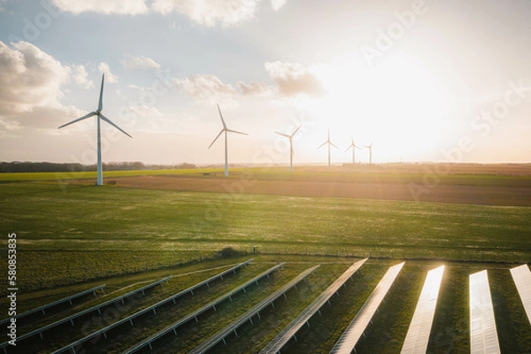 Obraz Wind turbines and solar panels farm in a field. Renewable green energy. Sunny landscape, electric energy generator for clean energy producing concept.