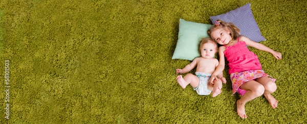 Fototapeta Two happy sisters lie on carpet