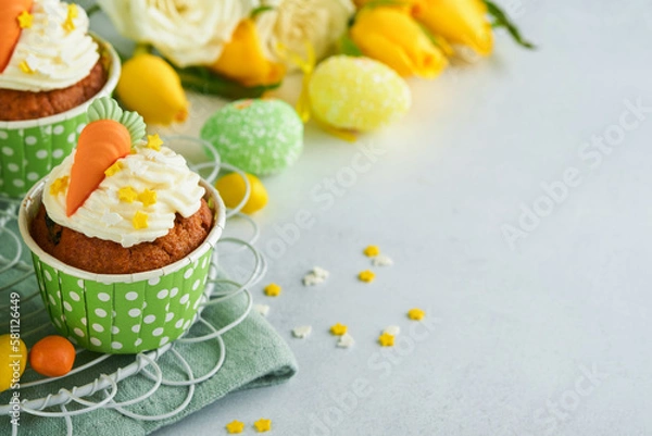 Fototapeta Carrot cake cupcakes for Easter. Carrot cupcakes with cream cheese frosting decorated with tiny marzipan carrots on white background. Happy Easter and spring holiday concept. Holydays homemade dessert
