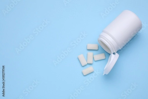 Fototapeta Jar with chewing gums on light blue background, flat lay. Space for text