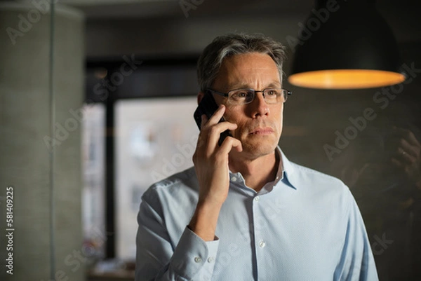 Obraz Businessman in office. Handsome man talking on phone at work.