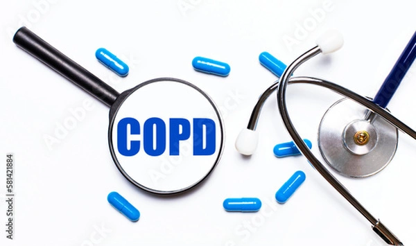 Obraz A doctor's workplace with various office supplies, such as a stethoscope, a magnifying glass with the text COPD and pills, top view.