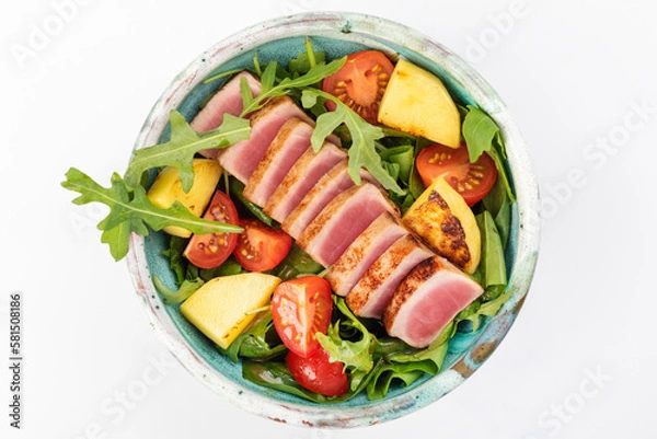 Fototapeta Poke bowl with tuna, cherry tomatoes, arugula, spinach, herbs, fried pineapples and soy sauce. Round bowl on a white background. Top view.