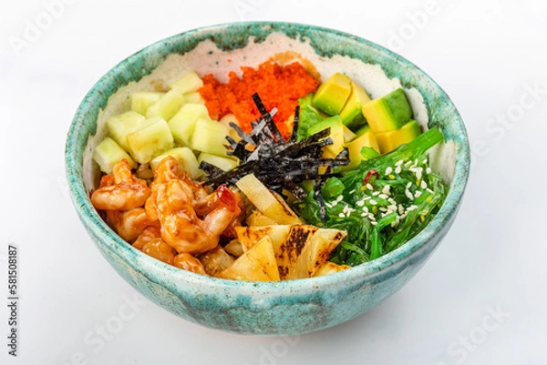 Fototapeta Bowl with fried shrimp, avocado, caviar, pineapple, chuka, cucumber, nori, and sesame seeds. Round green bowl on a white background. Close up 