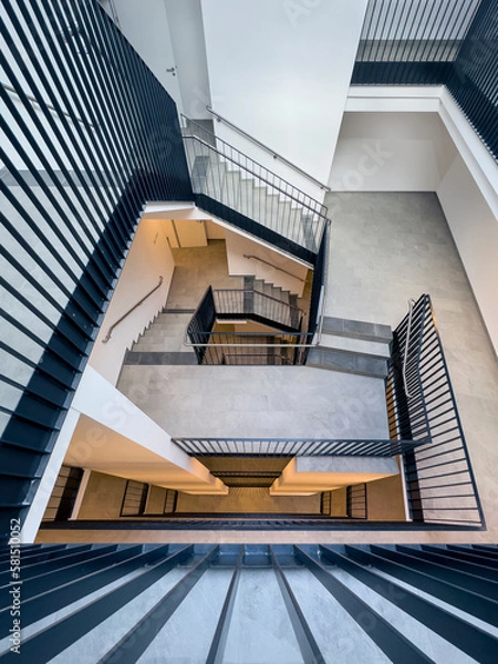 Obraz view from above into a stairwell of a multi-storey residential building with black steel railings