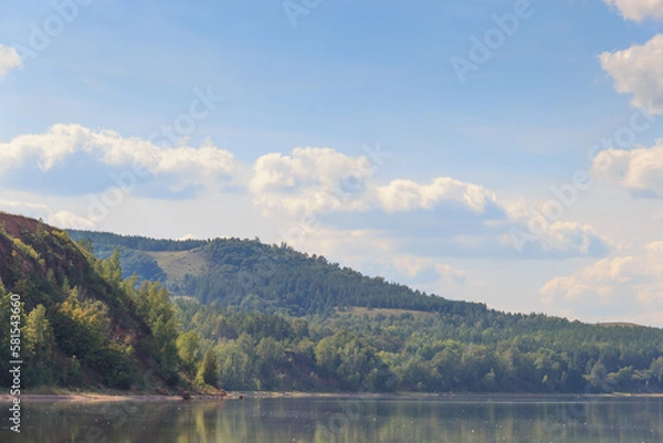 Fototapeta lake surrounded by green forest, hill with forest on background.Summer day